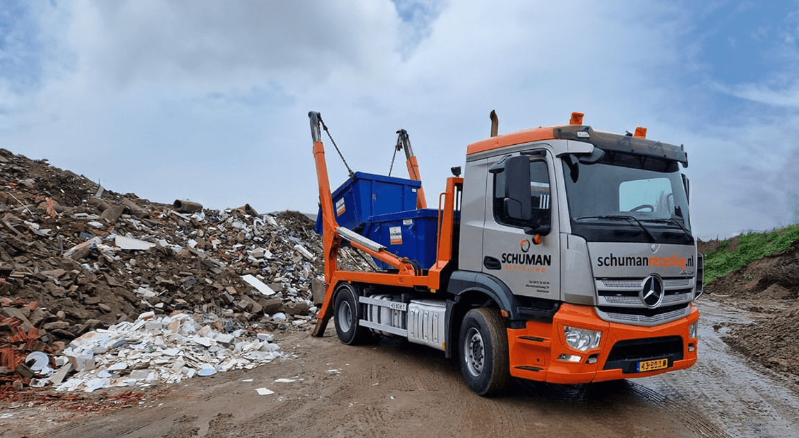 Afzetwagen van Schuman Recycling plaatst een container op het recyclingterrein